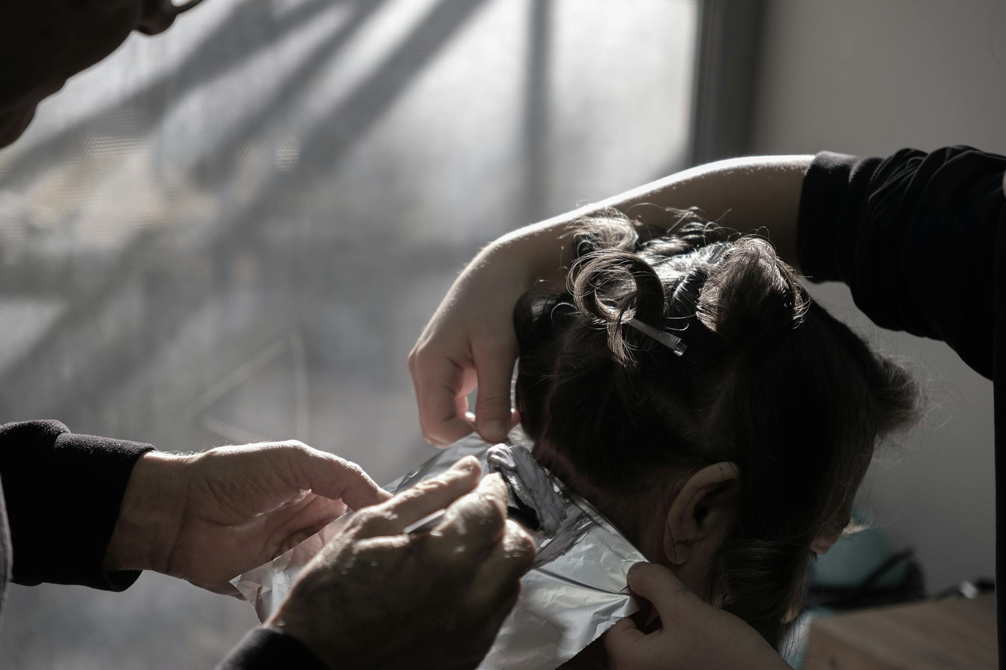 Home Expert hairdresser applying color highlights in a salon with natural lighting in İzmir, Türkiye.